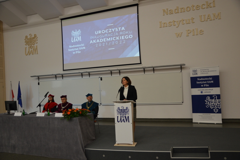 4 osoby na scenie podczas inauguracji roku akademickiego nadnoteckiego Instytutu UAM w Pile, w tym przemawiająca zastępca prezydenta miasta Piły.
