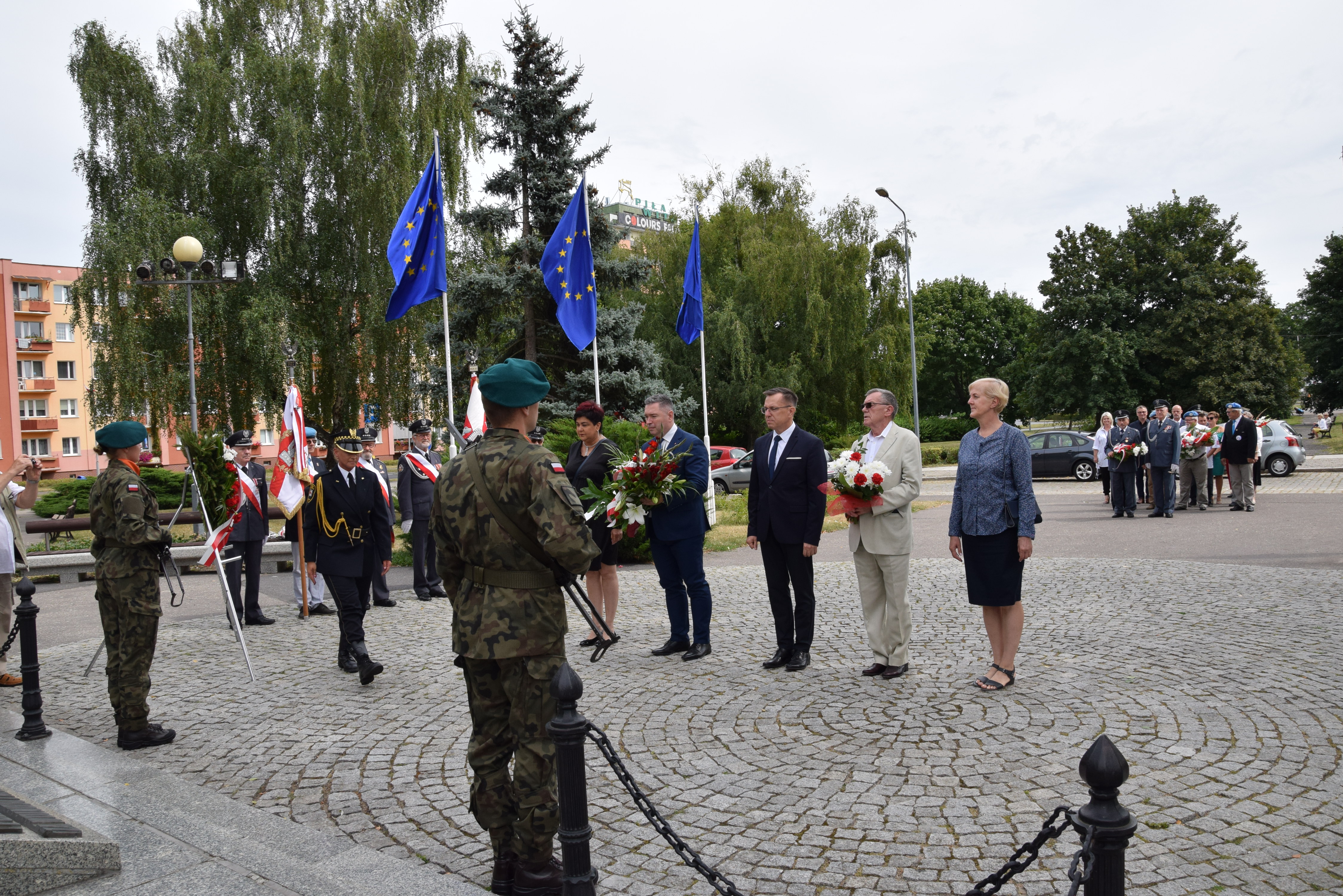 delegacja stoi przed pomnikiem, 2 żołnierzy po obu stronach pomnika pełni wartę honorową. 