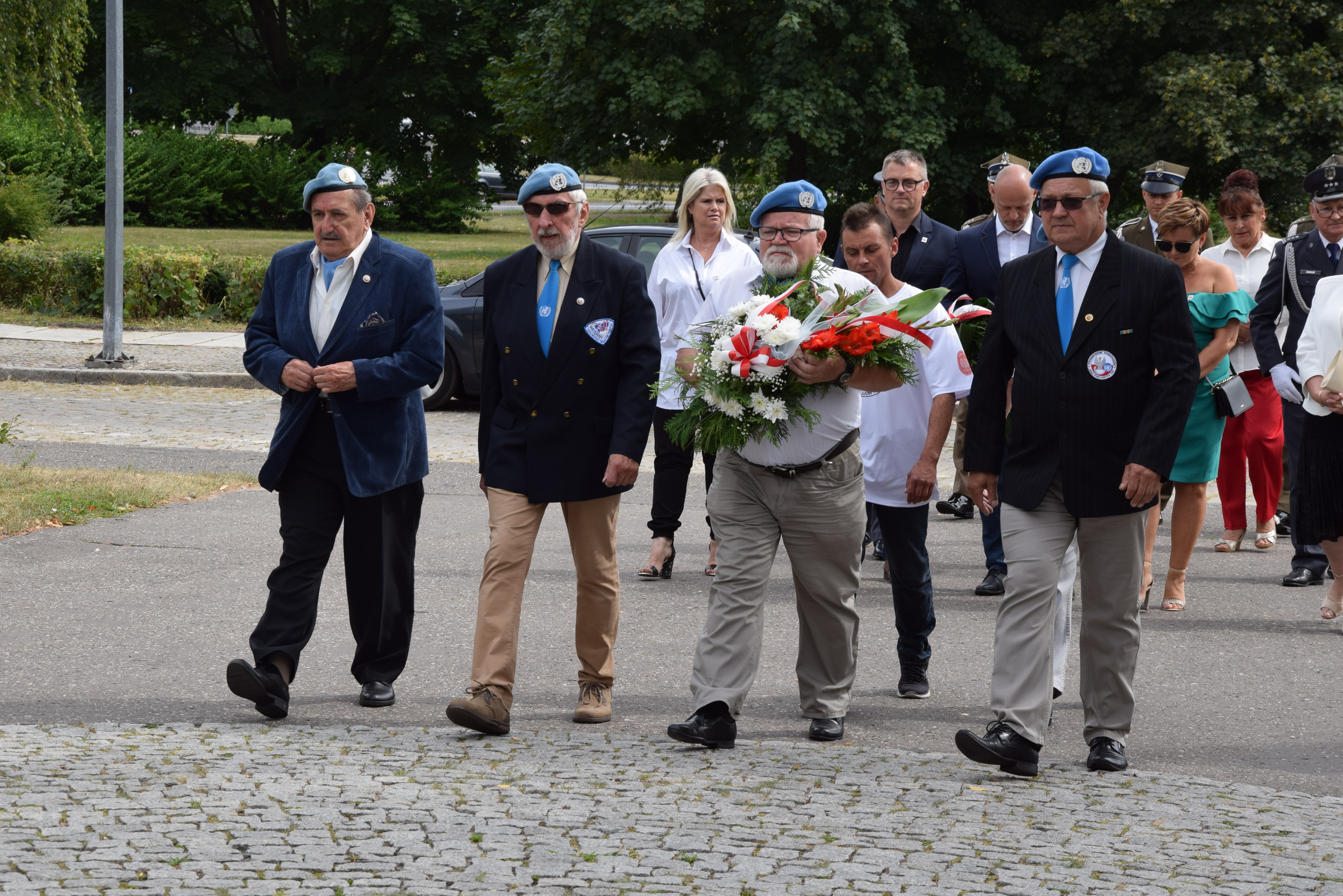 delegacja byłych żołnierzy misji ONZ zmierza w stonę pomnika, by złożyć kwiaty